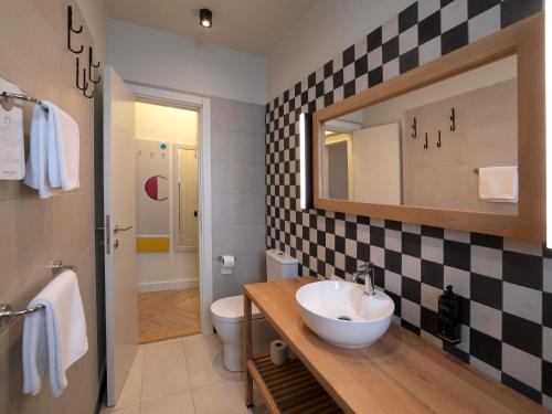 a bathroom with a sink and a toilet and a mirror at Mercure Belgrade Excelsior in Belgrade