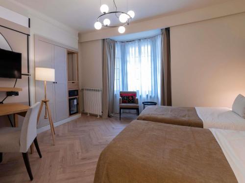a hotel room with two beds and a chair at Mercure Belgrade Excelsior in Belgrade