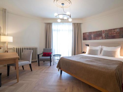 a hotel room with a large bed and a desk at Mercure Belgrade Excelsior in Belgrade