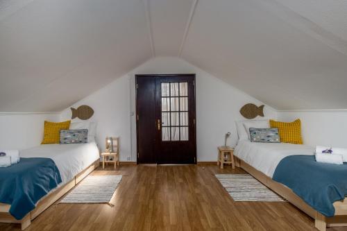 two beds in a room with white walls and wooden floors at Nest by the Lagoa, Carvalhal in Grândola