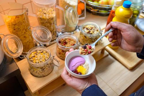 a person is eating food in a bowl on a table at ibis budget Hamburg St Pauli Messe - neu renoviert in Hamburg
