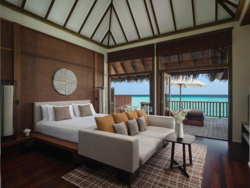 a bedroom with a white bed and a couch at Conrad Maldives Rangali Island in Mandhoo