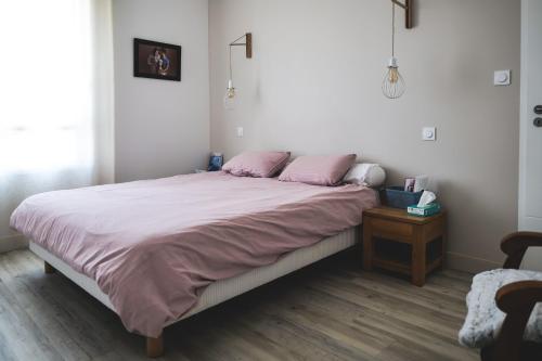 une chambre avec un grand lit avec des oreillers roses dans l'établissement Charmante maison moderne - quartier des Roses - 8 personnes, à La Rudelière