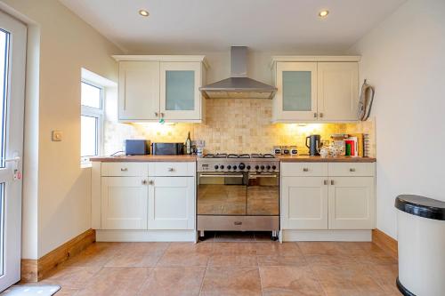 a kitchen with white cabinets and a stove at Finest Retreats - Sea Bank in Colwyn Bay