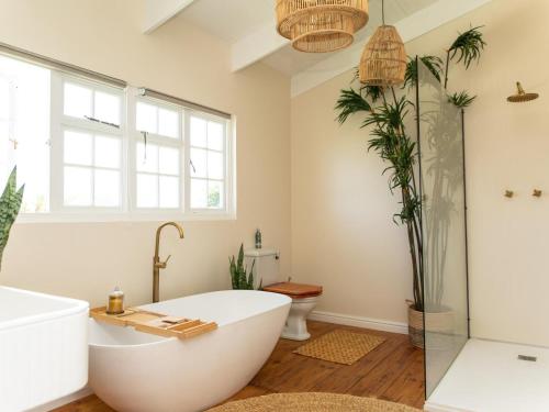 a bathroom with a white tub and a plant at Little Villa by Ideas Cartel in Hermanus