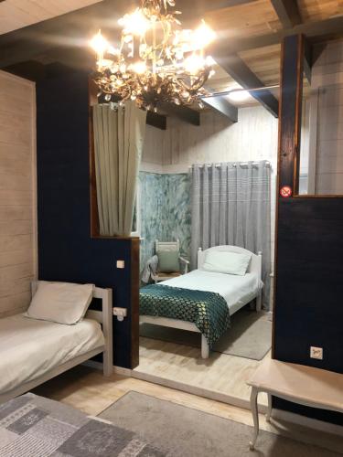 une chambre avec deux lits et un lustre dans l'établissement La Maison de Lavande, à Queaux