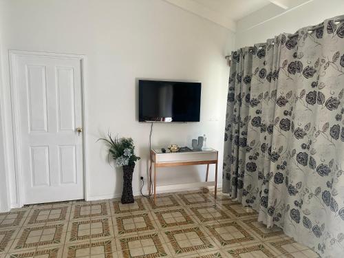 a room with a tv and a curtain and a table at Luxurious and Stylish House in Browns Plains