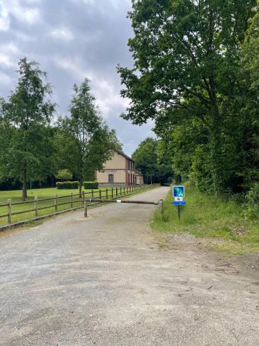 a dirt road with a fence and a blue sign at Gîte des Pommiers avec terrain de pétanque in Le Fresne-Poret