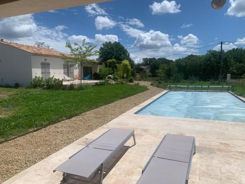 - une piscine avec deux bancs à côté d'une maison dans l'établissement A L'OMBRE DES GLYCINES maison avec piscine 7 personnes, à La Verdière