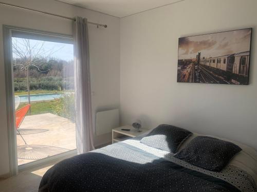 une chambre avec un lit et une fenêtre avec une photo de train dans l'établissement A L'OMBRE DES GLYCINES maison avec piscine 7 personnes, à La Verdière