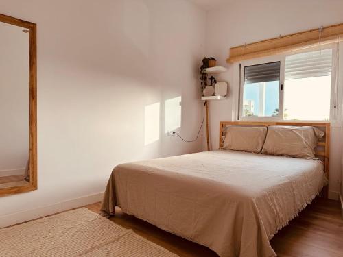Un dormitorio con una cama con ventana y espejo. en Apartamento acogedor con vistas al mar, en Los Cristianos