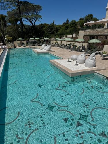 a swimming pool with blue water and chairs and umbrellas at Château Rose Golfe de Saint Tropez-Grimaud in Grimaud