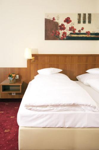 a bed with white sheets and pillows in a room at Waldhotel Nachtigall in Paderborn