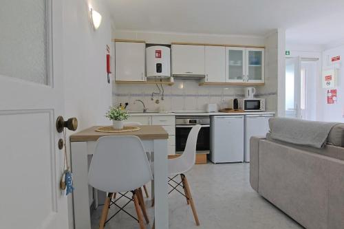 a kitchen and living room with a table and a couch at Maria's House in Costa da Caparica
