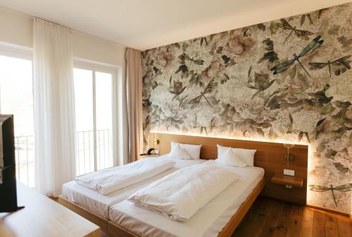 a bedroom with a large bed with a floral wall at B&O Parkhotel in Bad Aibling