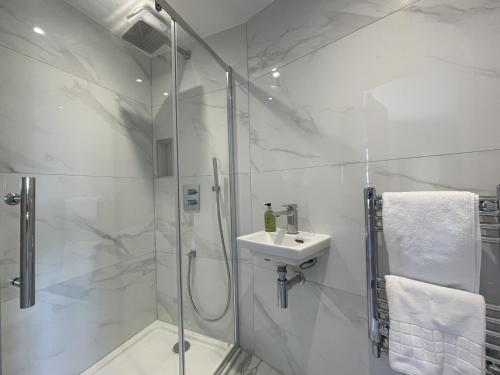 a white bathroom with a shower and a sink at Mill House in Braithwaite