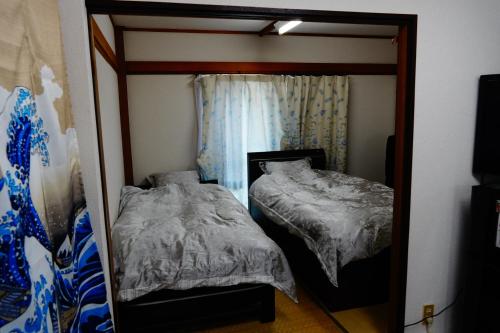 espejo reflejo de un dormitorio con 2 camas en MINPAKU-P 民泊p, en Izumisano