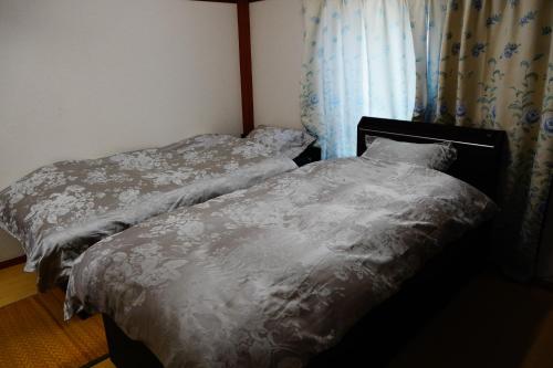 Dos camas individuales en una habitación con ventana. en MINPAKU-P 民泊p, en Izumisano