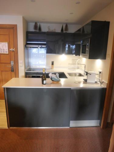 une cuisine avec des armoires noires et un comptoir blanc dans l'établissement Stunning 3 bed duplex in the heart of Arc 1950 village - sleeps 8, à Bourg-Saint-Maurice