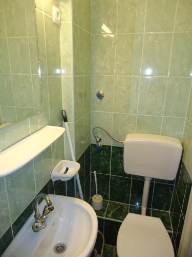 a green tiled bathroom with a toilet and a sink at Hotel Touring in Nagykanizsa