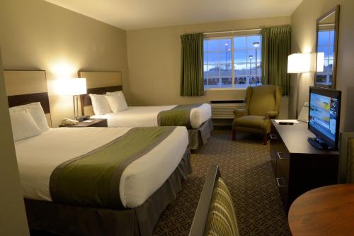 a hotel room with two beds and a flat screen tv at Hilltop Inn by Riversage in Billings