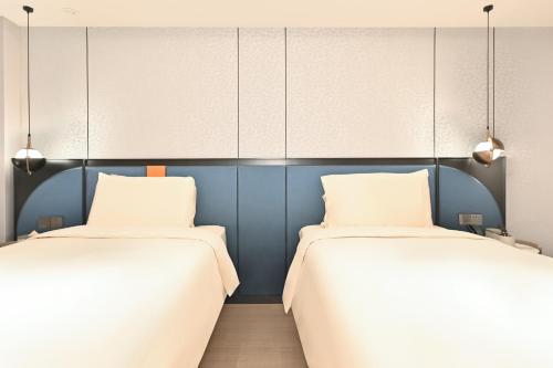 two beds in a room with blue walls at Atour X Hotel West Nanjing Road in Shanghai