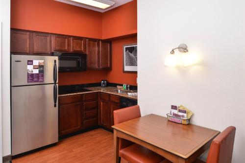a kitchen with a table and a stainless steel refrigerator at Residence Inn Columbia Northeast/Fort Jackson Area in Columbia