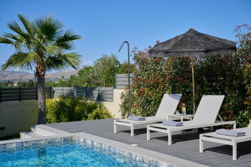 two chairs and an umbrella next to a swimming pool at Kyamon Luxury Villa - Peaceful Escape with Heated Pool near Chania! in Chania Town