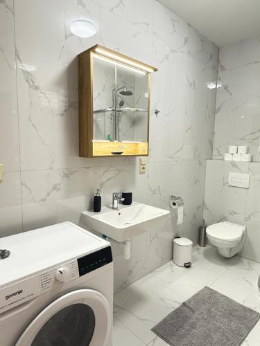 a white bathroom with a washing machine and a sink at Riverside Apartment Praha in Prague