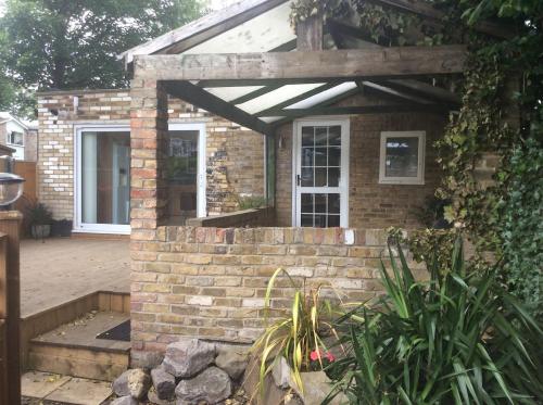 a brick house with awning and a patio at Garden bungalow - separate entrance in Watford