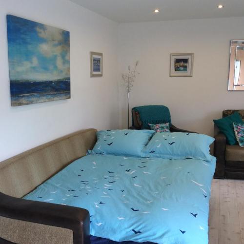 a bed with a blue sheet with fish on it at Garden bungalow - separate entrance in Watford