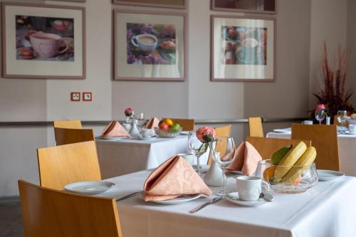 Un comedor con dos mesas con manteles blancos. en Hotel Junior Poděbrady, en Poděbrady
