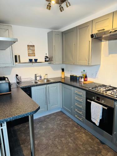 a kitchen with blue cabinets and a counter top at Fly Hi-Town Centre Apartment in Ifield
