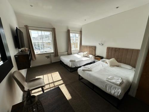 a hotel room with two beds and a chair at Somerset Hotel Baker Street London in London