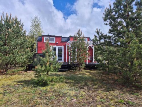 una casa rossa in un campo alberato di Tajnikowo Sekretny Tiny House Wasabi a Lubiana