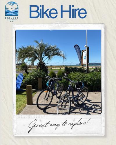 two bikes parked next to each other on a sidewalk at Baileys At The Beach in Whitianga