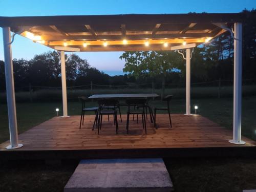 une terrasse en bois avec une table et des chaises sous une pergola dans l'établissement CHARMANT LOGEMENT ENTIER A LA CAMPAGNE, à Sencenac-Puy-de-Fourches