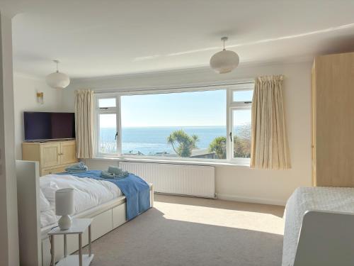 ドーチェスターにあるEast Creek - dog friendly beachside home with pool in Ringsteadの海が見える大きな窓のある寝室
