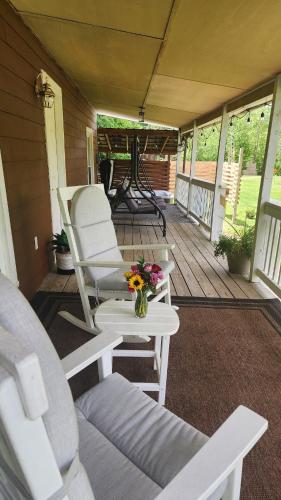 a porch with two chairs and a table with flowers at Red River Gorge Farmhouse 50 Acres in Stanton
