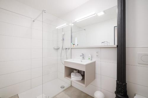 a white bathroom with a sink and a shower at Gasthaus Adler Konstanz in Konstanz