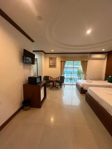 a hotel room with two beds and a table at SK Residence And Restaurant Patong in Patong Beach