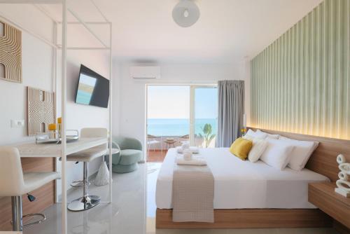 a bedroom with a bed and a desk and a view of the ocean at Stavros Beachfront Suites in Nea Kydonia