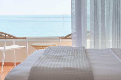 a bed in a room with a view of the ocean at Stavros Beachfront Suites in Nea Kydonia