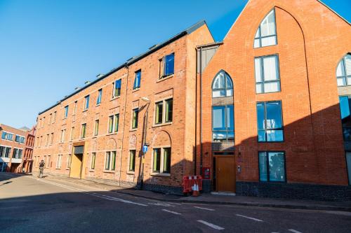 a red brick building with an archway on a street at Stylish New 2-Bed Apartment in JQ in Birmingham