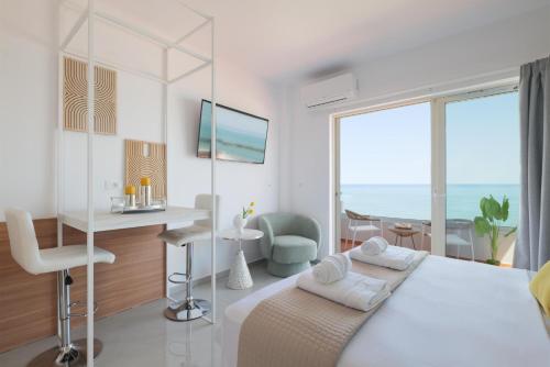 a white bedroom with a bed and a desk and a window at Stavros Beachfront Suites in Nea Kydonia