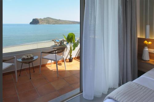a bedroom with a view of the ocean at Stavros Beachfront Suites in Nea Kydonia