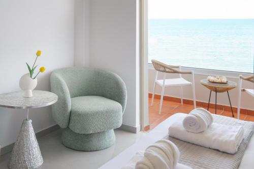 a living room with a green chair and a table at Stavros Beachfront Suites in Nea Kydonia