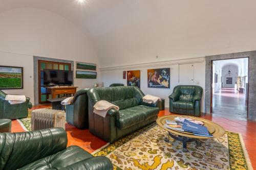 a living room with green leather furniture and a tv at Convento da Orada - Monsaraz in Monsaraz