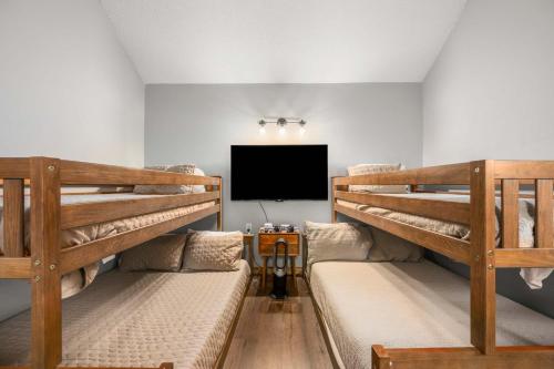 two bunk beds in a room with a flat screen tv at Renovated Ski In Out Condo King Bed Patio Grill in Ellicottville