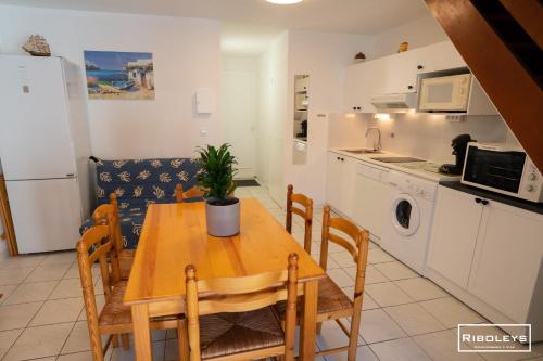 une cuisine et une salle à manger avec une table et des chaises en bois dans l'établissement Charmante maison climatisée à 500m de la plage, à Vias